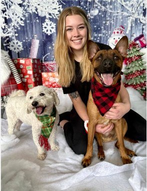 Happy Pets Palace team member with three dogs on a winter holiday portrait set
